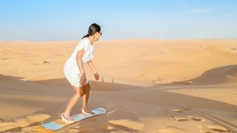 Teenager fährt Sandboard die Düne hinunter in der Wüste – Oman Reise mit Kindern