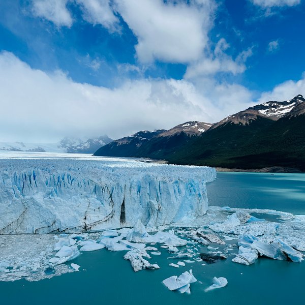 Der Perito Moreno Gletscher erstreckt sich majestätisch über das türkisfarbene Wasser, umgeben von schneebedeckten Bergen.