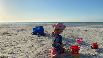 Mädchen baut im Sand und schaut auf das ruhige Meer – Mexiko Reise mit Kindern
