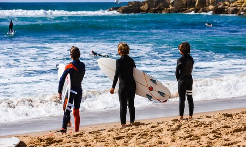Drei Kinder warten auf die nächste Welle zum surfen