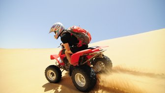 Ein Mann fährt auf einem Quad durch die Wüste - Namibia mit Kindern