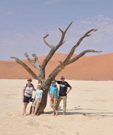 Eine Familie steht neben einem trockenen Baum in der Wüste - Namibia Rundreise mit Kindern