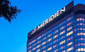 Das elegante Gebäude des Le Meridien in Neu-Delhi strahlt in der Dämmerung mit leuchtenden Fenstern und modernem Design.