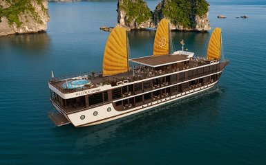 Ein elegantes Kreuzfahrtschiff mit gelben Segeln gleitet über das ruhige Wasser der Lan Ha Bucht, umgeben von grünen Felsen.