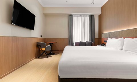 Ein modernes Hotelzimmer mit einem großen Doppelbett und einem Flachbildfernseher an der Wand, ideal für Erholung.