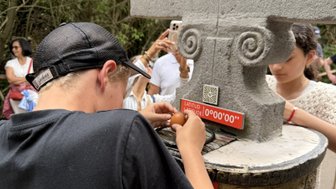 Ein Junge mit einer schwarzen T-Shirt untersucht einen Stein mit einer Inschrift über den Wendekreis des Krebses.