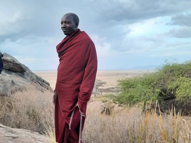 Massai-Mann steht auf einem Kopje des Olduvai Camps – Tansania mit Kindern