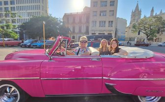 Drei Frauen sitzen in einem pinken Oldtimer-Cabrio in Havanna - Kuba mit Kindern