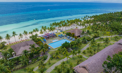Ein atemberaubender Blick auf einen tropischen Strand mit klarem Wasser und einem einladenden Pool in der Mitte der Anlage.