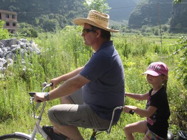 Vater und Kind entdecken gemeinsam die Landschaft von Yangshuo auf einer Fahrradtour – China Familienreise