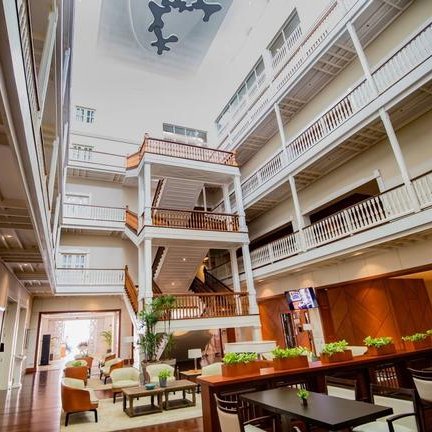 Ein eleganter Innenraum eines Hotels, geprägt von hellen Farben und einem großen offenen Atrium mit mehreren Etagen.