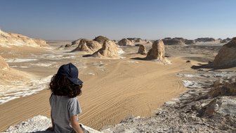 Kind sitzt auf der Weißen Wüste und genießt den Ausblick - Ägypten Reise mit Kindern