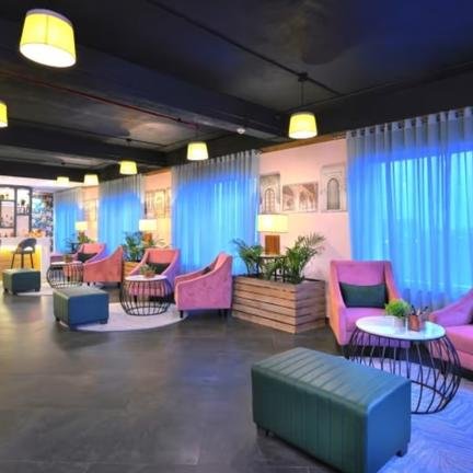 Ein stilvolles Lounge-Interieur mit pinken Sesseln, modernen Tischen und einer gut beleuchteten Bar im Hintergrund.