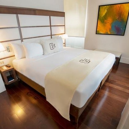 Ein elegantes Hotelzimmer mit einem großen Bett, das mit weißen Kissen und einer dekorativen Bettdecke geschmückt ist.