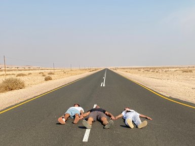 Eine Familie liegt auf einer Straße in der Wüste - Namibia mit Jugendlichen