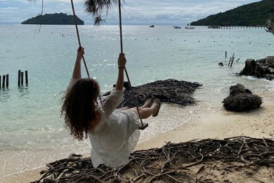 Ein Mädchen genießt das Schaukeln am Strand des Nexus Resorts – Malaysia & Borneo Reise mit Kindern
