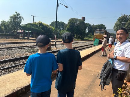 Guide und zwei Reisende Kinder beobachten die Einfahrt der Eisenbahn Death Train am Bahnsteg 