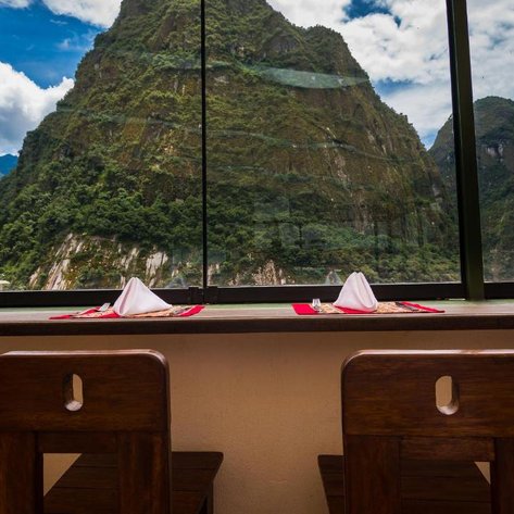 Ein eleganter Tisch mit weißen Servietten und rotem Tischläufer bietet einen atemberaubenden Blick auf die grünen Berge.