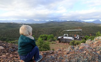 Kind blickt neugierig auf die Landschaft in der Buffelsdrift Game Lodge – Garden Route mit Kindern