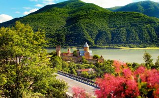 Eine malerische Landschaft mit einem historischen Kloster, umgeben von üppigen grünen Bergen und einem ruhigen See.