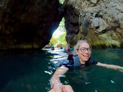 Eine Gruppe von Schwimmern erkundet eine malerische Wasseröffnung zwischen den Felsen, umgeben von üppigem Grün.