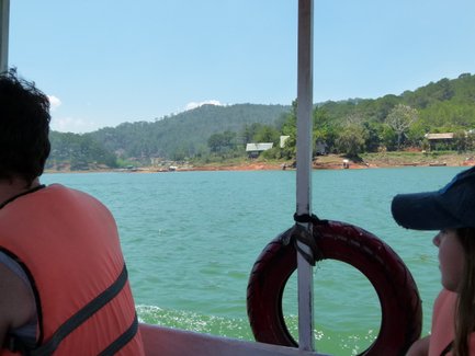 Ein Boot fährt über das ruhige Wasser eines Sees, umgeben von grünen Hügeln und einer malerischen Landschaft.