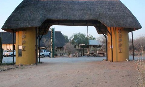 Der Eingangsbereich des Oppi Koppi Restcamps zeigt ein traditionelles Strohdach und farbenfrohe Wände.