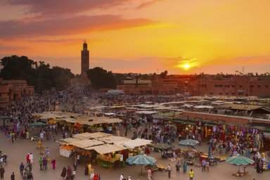 Djemaa el Fna Platz mit Menschen und Marktständen im Licht des Sonnenuntergangs in Marrakesch – Marokko Reise mit Kindern