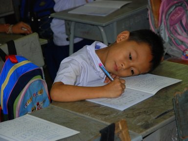 Schulkind in Thailand bei der Arbeit an seinem Schulheft – Thailand Familienreise