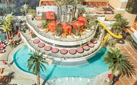 Ein lebhafter Poolbereich mit Palmen, bunten Liegen und einem aufregenden Wasserrutschen, ideal für Entspannung und Spaß.