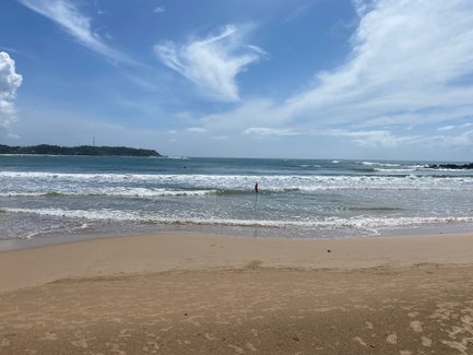 Wellen treffen auf den goldenen Sandstrand unter blauem Himmel – Sri Lanka Familienreise