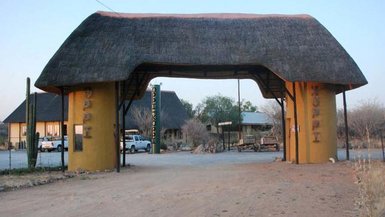 Der Eingangsbereich des Oppi Koppi Restcamps zeigt ein traditionelles Strohdach und farbenfrohe Wände.