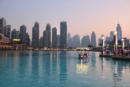 Eine traditionelle Dhow fährt sanft über das ruhige Wasser des Dubai Creeks, umgeben von beeindruckenden Wolkenkratzern.