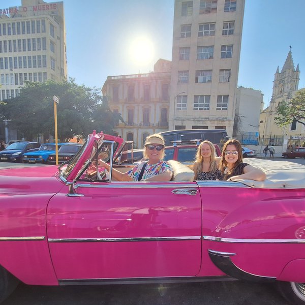 Drei Frauen sitzen in einem pinken Oldtimer-Cabrio in Havanna - Kuba mit Kindern