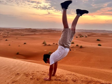 Junge macht Handstand in der Wahiba-Wüste beim Sonnenuntergang – Oman Reise mit Kindern