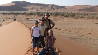 Eine Familie steht auf einer Düne  in der Wüste - Namibia Urlaub mit Kindern