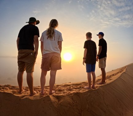 Familie genießt den Sonnenuntergang in der Sandwüste – Oman Familienreise