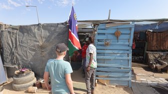 Ein Junge steht neugierig vor einer einfachen Hütte von Einheimischen- Namibia mit Kindern