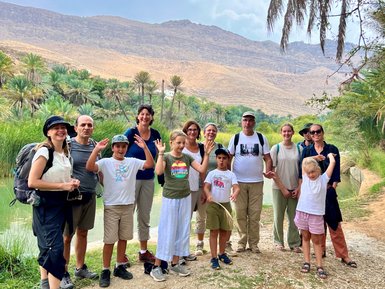 Eine Gruppe mit Familien erkundet die Felslandschaft des Wadi Shab – Oman Reise mit Kindern
