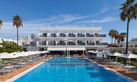 Ein einladender Poolbereich mit blauen Wasser und Sonnenschirmen, umgeben von Palmen und einem modernen Hotel im Hintergrund.