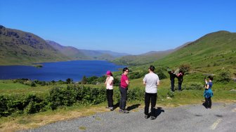 Eine Gruppe von fünf Personen steht an einem malerischen Aussichtspunkt mit Blick auf den Lough Nafoey und die umliegenden Berge.