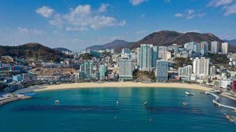 Ein atemberaubender Blick auf den Strand von Songdo, umgeben von modernen Hochhäusern und sanften Hügeln im Hintergrund.