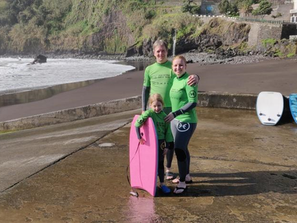Eine Familie steht am Strand von Madeira, bereit zum Bodysurfen, mit einem pinken Bodyboard in der Hand des Kindes.