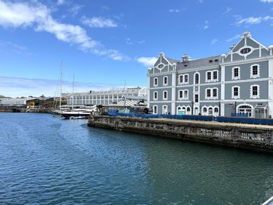 Ein malerischer Hafen in Kapstadt mit historischen Gebäuden und Yachten, unter einem strahlend blauen Himmel.