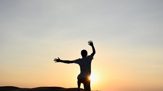 Silhouette eines Jungen beim Sonnenuntergang in der Wüste – Oman Reise mit Kindern