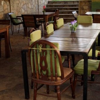 Ein einladender Außenbereich mit Holztischen und bunten Stühlen, ideal für gesellige Zusammenkünfte.