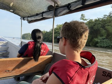 Zwei Personen in roten Schwimmwesten sitzen in einem Boot und genießen die Aussicht auf den Fluss und die umgebende Natur.