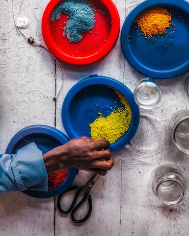 Bunte Perlen sorgfältig nach Farben sortiert bei Shanga – Tansania mit Kindern