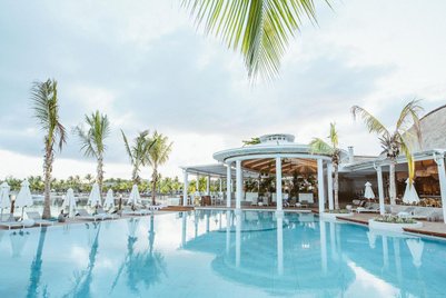 Ein luxuriöser Poolbereich mit Palmen und Liegen, umgeben von einem eleganten Restaurant in Mauritius.