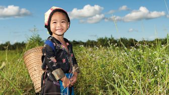 Einheimisches Kind zwischen grünen Teesträuchern in einer Teeplantage – China mit Kindern
